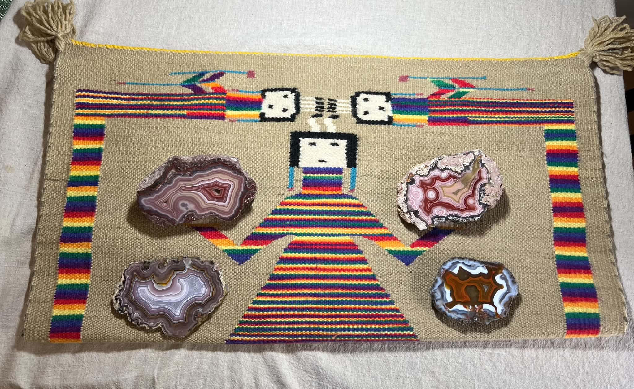 Four polished agate specimens displayed on a colorful woven textile
